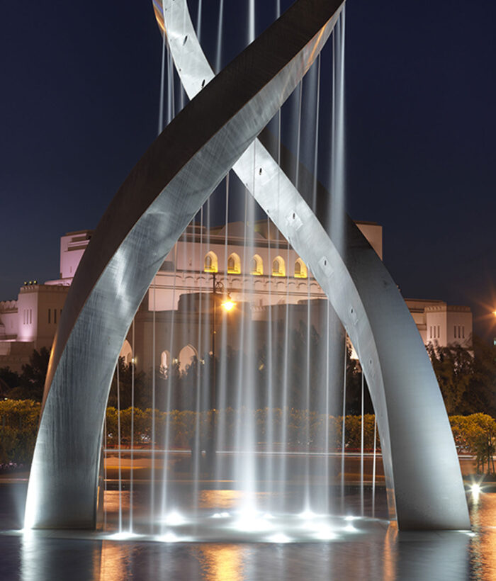 Lit up sculpture standing in water at night time in Oman