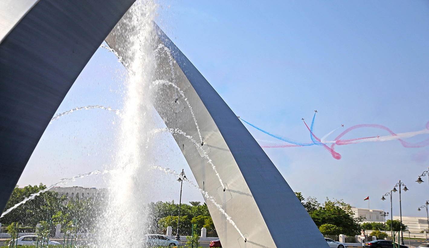 Close up of arches sculpture with Red Arrows flying in background in blue sky