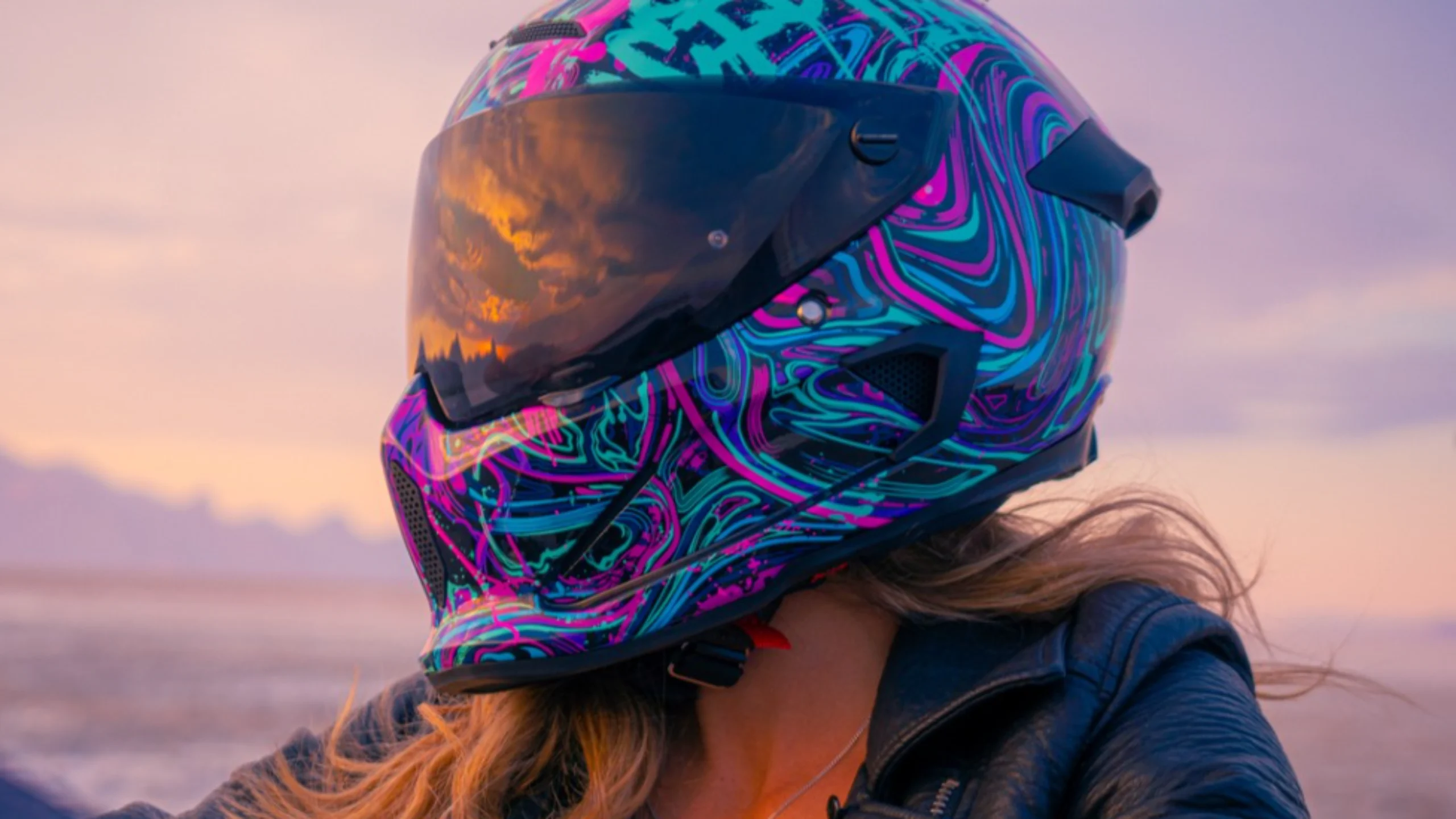 Woman in motorcycle helmet with sunset